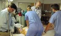 A group of doctors and nurses are gathered around an injured patient.