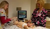 A woman in pajamas is playing with an infant.